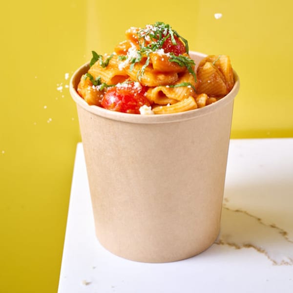 Pasta Lab NYC's pasta in a cup, topped with sauce, tomatoes, cheese, and basil.
